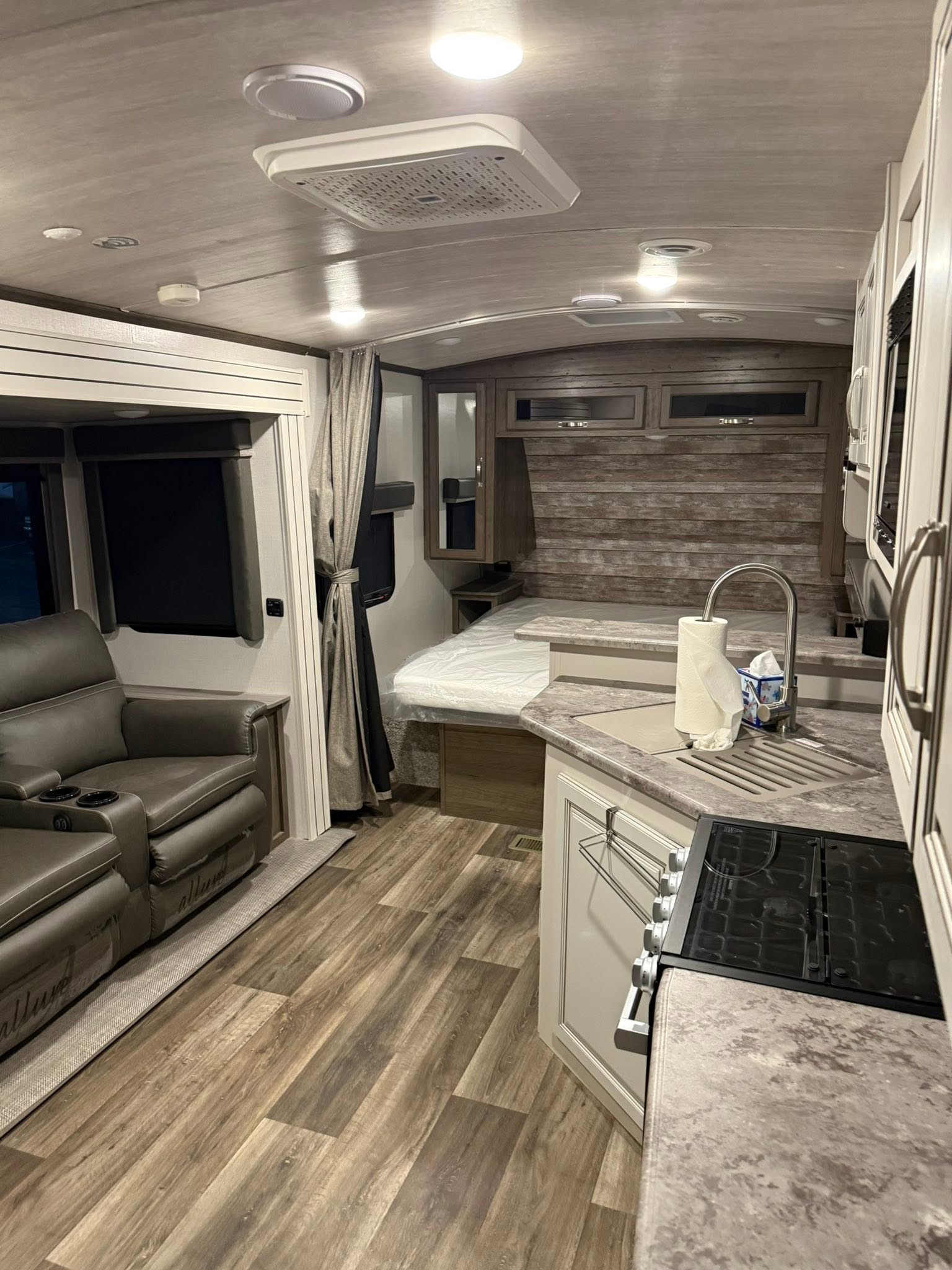 Keystone Cougar living area with two recliners, the kitchen counter, and the bed beyond